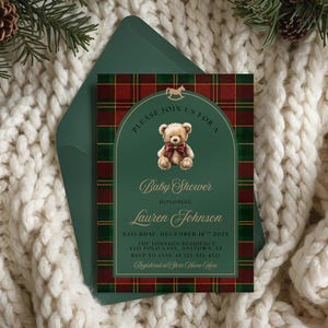 May include: Baby shower invitation with a green and red tartan design. The invitation features a teddy bear illustration and the text "Baby Shower" and event details. The invitation is placed inside a green envelope.