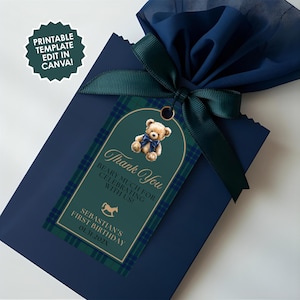 May include: A navy blue gift bag tied with a dark green ribbon and a matching tag. The tag features a teddy bear illustration, the text "Thank You," and "Beary much for celebrating with us!" The tag also includes the text "Sebastian's First Birthday 01.31.202X."