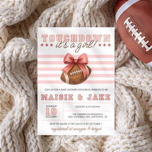 May include: A baby shower invitation with a football theme. The invitation features the text "TOUCHDOWN it's a girl!" in pink, along with a watercolor football and bow. The invitation includes details for Maisie & Jake's baby shower.