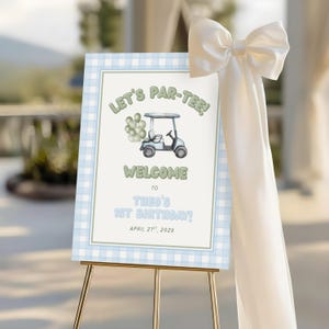 Puede incluir: Un letrero rectangular de bienvenida para cumpleaños con borde de cuadros vichy azul claro, ilustración de carrito de golf, globos verdes y el texto: LET'S PAR-TEE! WELCOME TO THEO'S 1ST BIRTHDAY! APRIL 21ST, 2029. Un gran lazo de satén blanco.