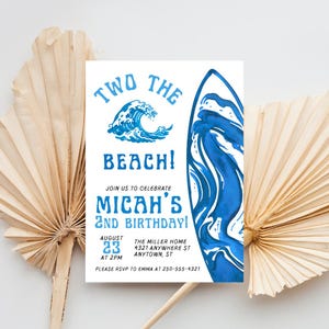 Puede incluir: Una invitación con temática de playa con gráficos de acuarela azules. El texto dice "Two the Beach!" y anuncia el segundo cumpleaños de Micah. Incluye fecha, hora, lugar e información de RSVP. La invitación está rodeada de hojas de palma secas.