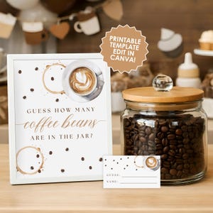 May include: A white framed sign with the text "GUESS HOW MANY coffee beans ARE IN THE JAR?" is next to a glass jar filled with coffee beans. A small card with space for a guess and name is also present. The sign has coffee cup stains.