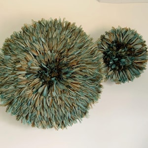 Peut inclure: Deux décorations murales en plumes. La plus grande mesure environ 60 cm de diamètre, et la plus petite environ 30 cm. Les plumes sont un mélange de bleu sarcelle, de marron et de beige, créant un aspect texturé et naturel.