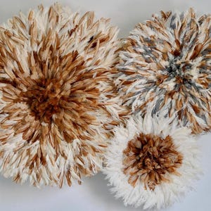 Peut inclure: Trois décorations murales circulaires en plumes. La plus grande est ornée de plumes blanches et marron, tandis que les autres combinent des plumes blanches, marron et grises. Ces pièces décoratives sont conçues pour être accrochées au mur.