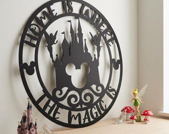 May include: Black metal wall art with the text "HOME IS WHERE THE MAGIC IS" encircling a castle silhouette with Mickey Mouse ears. Decorative figurines of a castle, fairy, and glass slipper are on a wooden surface.