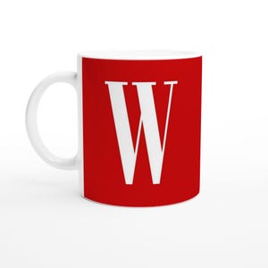 May include: White ceramic mug with a red background displaying a large white letter "W". The mug has a white handle and is designed for hot drinks. The design is simple and bold, suitable for everyday use.