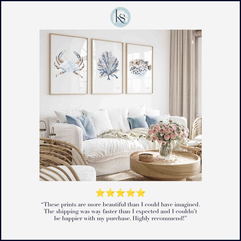 May include: Three framed watercolour prints of a crab, coral, and a pufferfish in blue and brown tones. The prints are hanging on a white wall above a white sofa with blue cushions.