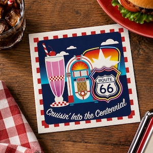 May include: A square paper napkin featuring a red and white chequered border. The central graphic displays a pink milkshake, a colourful jukebox, and a Route 66 road sign. The text Cruisin' Into the Centennial is printed in white script at the bottom.