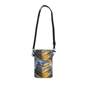 May include: A vertical crossbody bag with a black strap and a flap closure. The bag features a watercolour design of a stack of books with gold-coloured pages and a starry background. The bag is designed to hold a phone or small items.