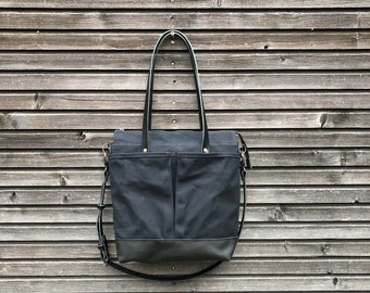 Black waxed canvas tote bag with leather bottom handles and cross body strap