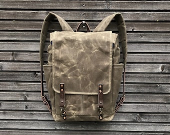 May include: A brown canvas backpack with leather straps and buckles. The backpack has a flap closure and a large main compartment.
