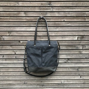 Black waxed canvas tote bag with leather bottom handles and cross body strap