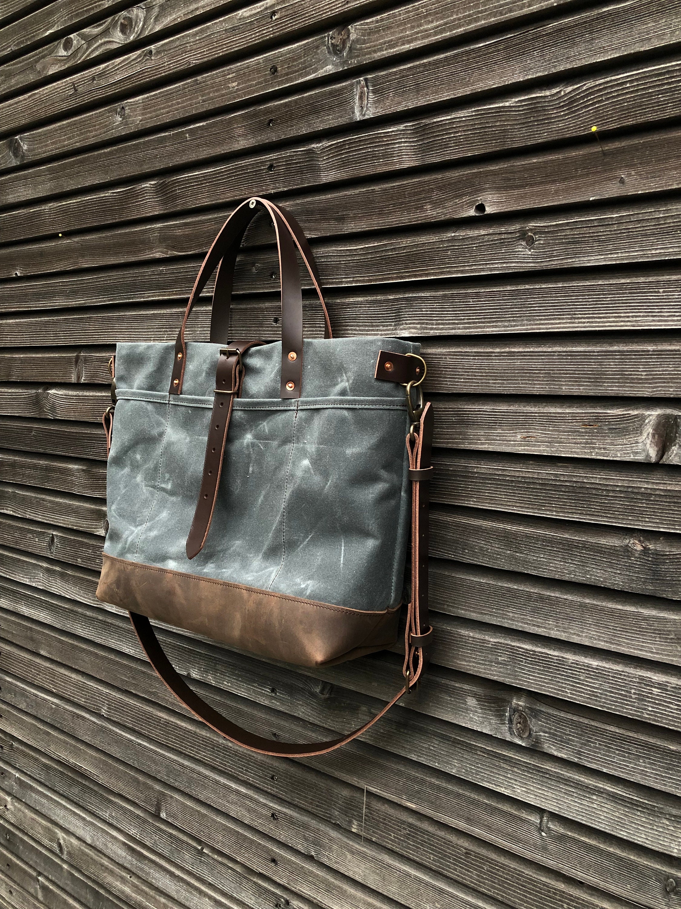 Black waxed canvas tote bag with leather bottom handles and cross