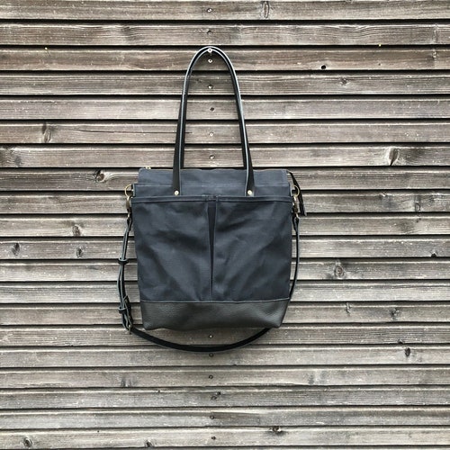 Black waxed canvas tote bag with leather bottom handles and cross body strap
