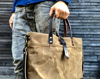 Black waxed canvas tote bag with leather bottom handles and cross