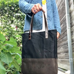 Tote bag made in black waxed canvas with leather base and zipper pocket inside