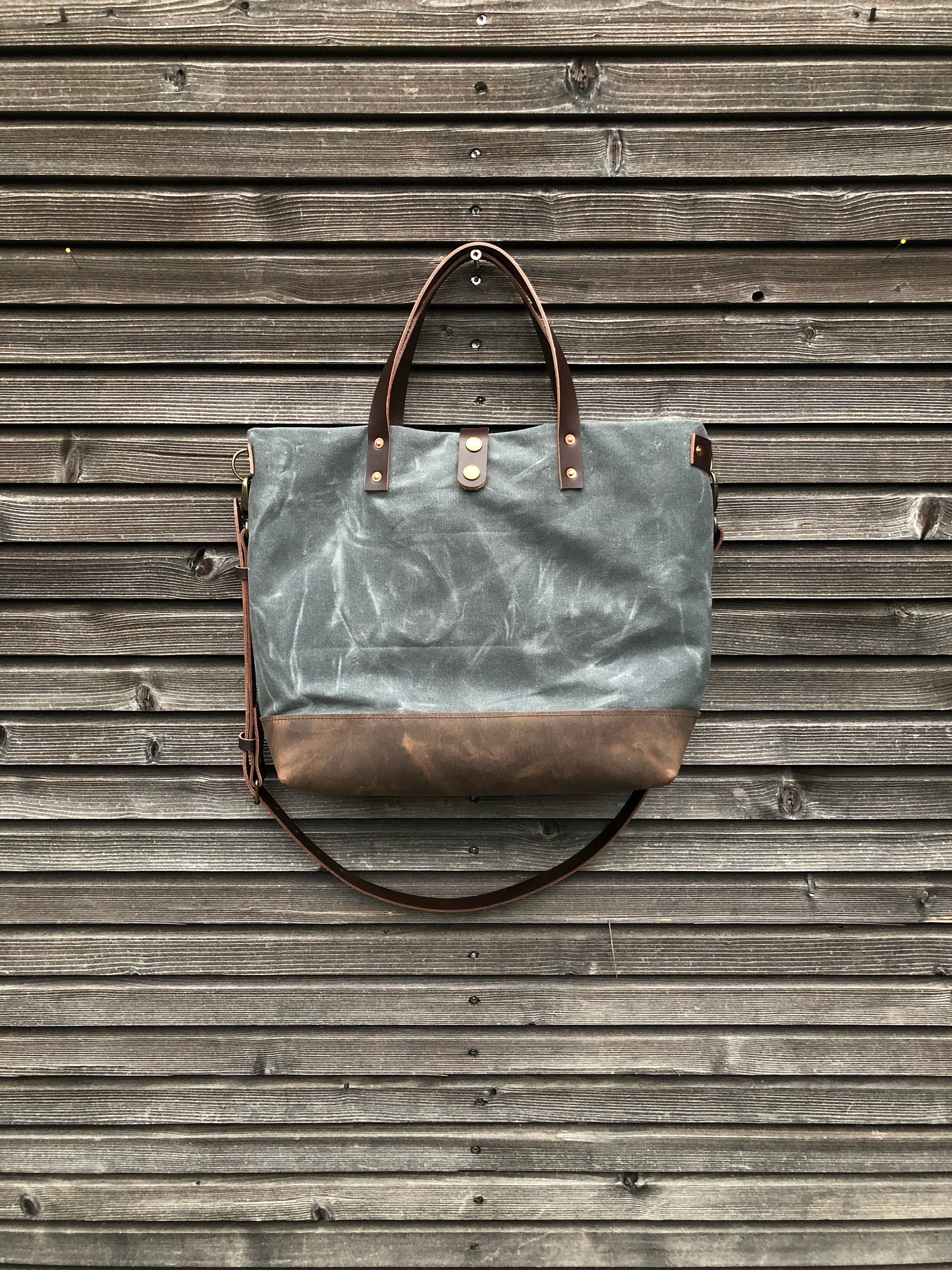 Black waxed canvas tote bag with leather bottom handles and cross