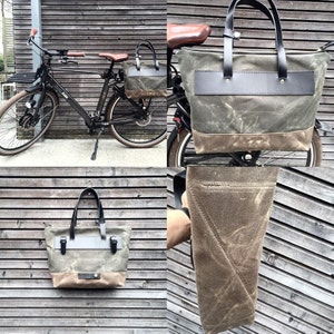 May include: A green canvas tote bag with brown leather accents and a black leather strap. The bag is shown on a bicycle and on a wooden surface.