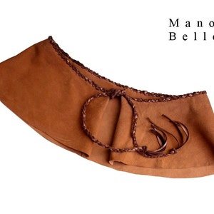 May include: A brown suede belt with a braided leather trim and fringe detail. The belt is tied in the front with a knot.