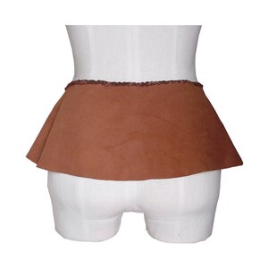 May include: A brown suede skirt with a ruffled hem and a decorative trim around the waistband.