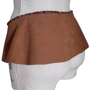 May include: A brown suede skirt with a braided leather waistband. The skirt is gathered at the waist and has a flared shape.