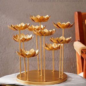 Op de afbeelding: Een gouden metalen lotusbloem kandelaar met meerdere bloemvormige kaarshouders. De kandelaar heeft een ronde basis en slanke stelen. De tekst "Wholesome Handmade" is zichtbaar op de achtergrond.