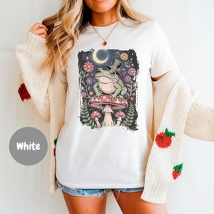 Strana maglietta con rana nella foresta incantata, maglietta grafica cottagecore con rana, maglietta magica con fungo e luna, top stravagante con estetica naturalistica, regalo unisex
