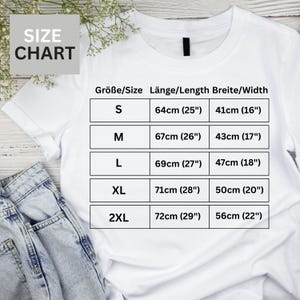 A white t-shirt with a size chart printed on it, along with a pair of denim jeans.