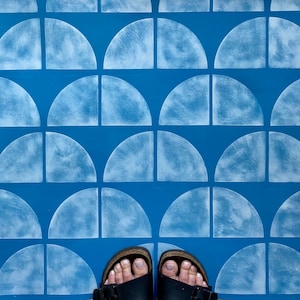 May include: A blue floor with white semi-circle shapes painted on it. Two brown sandals with black straps are on the floor.