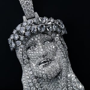 May include: A diamond-encrusted pendant in the shape of Jesus's face. The pendant features a detailed depiction of Jesus with a crown of thorns and long hair. The pendant is made of silver or white gold and is covered in numerous small diamonds.