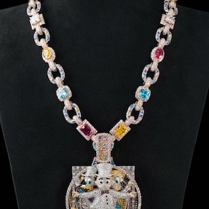 May include: A diamond-encrusted pendant necklace featuring a cartoon character design. The chain is composed of links with colorful gemstones. The pendant showcases a character in a top hat and bow tie, with two other characters on either side.