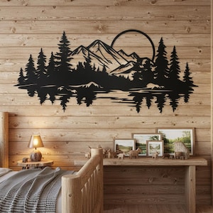 May include: Black metal wall art showing a mountain range, trees, and a sun or moon over a lake. The artwork is mounted on a wooden wall. The scene is a silhouette, creating a rustic, natural aesthetic.