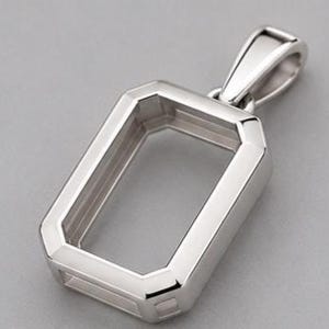 May include: A polished silver-toned metal pendant setting featuring a rectangular frame with bevelled edges and a sturdy integrated bail at the top. The hollow centre is designed to hold a gemstone or insert, showcasing a clean, metallic finish.