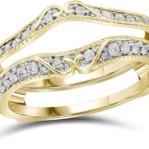 Könnte beinhalten: Ein goldfarbener Ringschutz mit geschwungenem Design. Der Ringschutz ist mit kleinen, klaren Edelsteinen besetzt und weist dekorative Wirbel auf. Das Band hat einen strukturierten Rand.