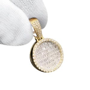 Könnte beinhalten: Goldener Anhänger mit rundem, diamantbesetztem Gesicht. Der Anhänger hat eine kleinere, diamantbesetzte Schlaufe für eine Kette. Die Diamanten sind in einen goldenen Rahmen gefasst.