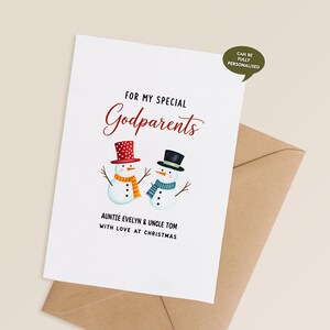 Puede incluir: Una tarjeta de felicitación blanca con el texto "FOR MY SPECIAL Godparents" en escritura roja. Dos muñecos de nieve con sombreros y bufandas están ilustrados debajo del texto. La tarjeta está personalizada con "AUNTIE EVELYN & UNCLE TOM WITH LOVE AT CHRISTMAS".