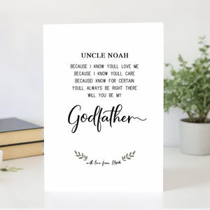 Puede incluir: Una tarjeta blanca con el texto "UNCLE NOAH" en la parte superior. Debajo, la tarjeta dice "BECAUSE I KNOW YOULL LOVE ME...WILL YOU BE MY Godfather". La tarjeta está decorada con un diseño de hojas y las palabras "with love from Elijah".