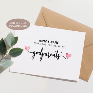 Puede incluir: Una tarjeta de felicitación blanca con el texto "NAME & NAME THANK YOU FOR BEING MY godparents" en escritura negra. Dos corazones rosas de acuarela flanquean la palabra "godparents". Un sobre marrón está detrás de la tarjeta. El texto "CAN BE FULLY PERSONALISED" está en un óvalo marrón claro.