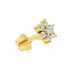 May include: A gold-colored stud earring featuring a flower design with seven clear, round-cut gemstones. The earring has a post and a flower-shaped backing. The gemstones are set in a cluster, creating a sparkling effect.