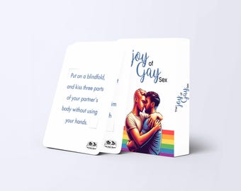 Könnte beinhalten: Ein weißes Box-Set mit dem Titel "joy of Gay Sex" mit einem Regenbogenstreifen und einer Illustration von zwei sich umarmenden Männern. Das Set enthält Karten mit Anweisungen. Auf einer Karte steht: "Setzen Sie eine Augenbinde auf und küssen Sie drei Teile des Körpers Ihres Partners, ohne Ihre Hände zu benutzen."