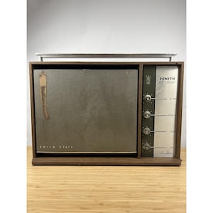 Puede incluir: Radio Zenith Solid State vintage con marco de madera. La radio tiene una cara plateada con perillas para balance, volumen, agudos y graves. La radio tiene una barra plateada en la parte superior.