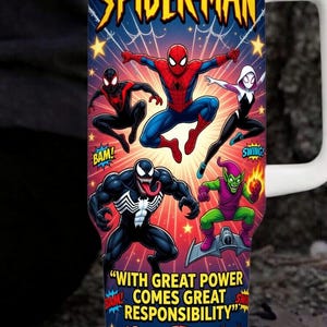 Op de afbeelding: Een beker met witte handgreep met een levendig Spider-Man-ontwerp. De beker toont verschillende Spider-Man-personages, waaronder Venom en de Green Goblin, met de tekst "WITH GREAT POWER COMES GREAT RESPONSIBILITY".