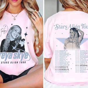 Puede incluir: Camiseta rosa claro con una imagen en blanco y negro de Freya Skye. La parte delantera de la camiseta muestra "freya skye STARS ALIGN TOUR" en texto azul claro. La parte trasera de la camiseta enumera las fechas y lugares de la gira.
