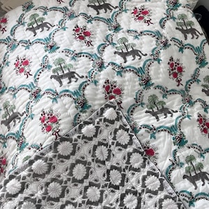 Può includere: Coperta trapuntata bianca con un motivo ripetuto di pantere grigie, palme e bouquet floreali rossi. Il bordo presenta volute turchesi. Il lato posteriore mostra un motivo floreale grigio e bianco.