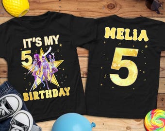 May include: Black t-shirts with gold text and graphics. One shirt says "IT'S MY 5 BIRTHDAY" with a star and cartoon figures. The other shirt says "MELIA 5". Accessories include sunglasses, a pineapple, and a blue balloon.