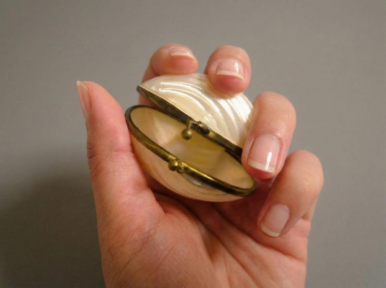 Open vintage clam shell jewelry box in hand, mother of pearl trinket box with brass trim and clasp