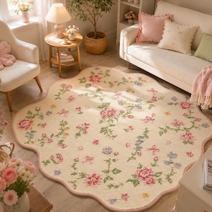 May include: A cream-colored area rug with a scalloped edge, featuring a repeating pattern of pink, blue, and yellow flowers with green vines and small pink bows scattered across the surface. The rug has a soft texture and a floral design.