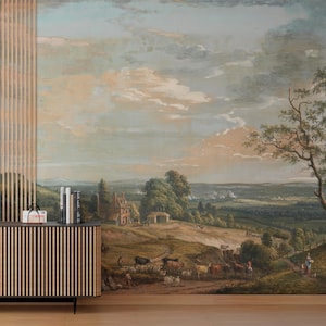 Puede incluir: Un mural de pared que presenta una pintura de paisaje pastoral con un &aacute;rbol grande a la derecha, colinas verdes, una casa peque&ntilde;a y un reba&ntilde;o de ganado pastando en primer plano bajo un cielo vasto y nublado. Un mueble de madera con listones est&aacute; delante.