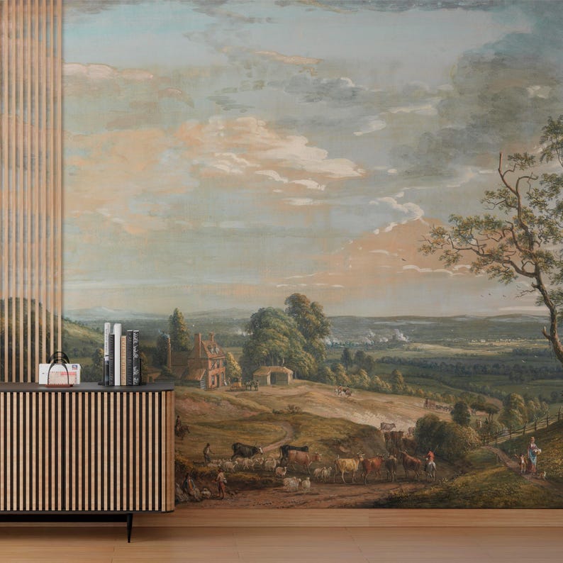 Puede incluir: Un mural de pared que presenta una pintura de paisaje pastoral con un &aacute;rbol grande a la derecha, colinas verdes, una casa peque&ntilde;a y un reba&ntilde;o de ganado pastando en primer plano bajo un cielo vasto y nublado. Un mueble de madera con listones est&aacute; delante.