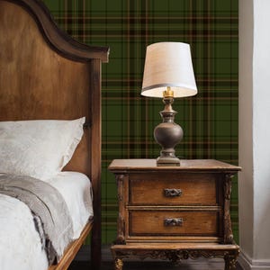 Könnte beinhalten: Ein Schlafzimmer mit einem Holzbett und einem Nachttisch. Der Nachttisch hat zwei Schubladen und eine Lampe mit beigem Lampenschirm. Die Wand hinter dem Nachttisch ist mit grüner karierter Tapete dekoriert.